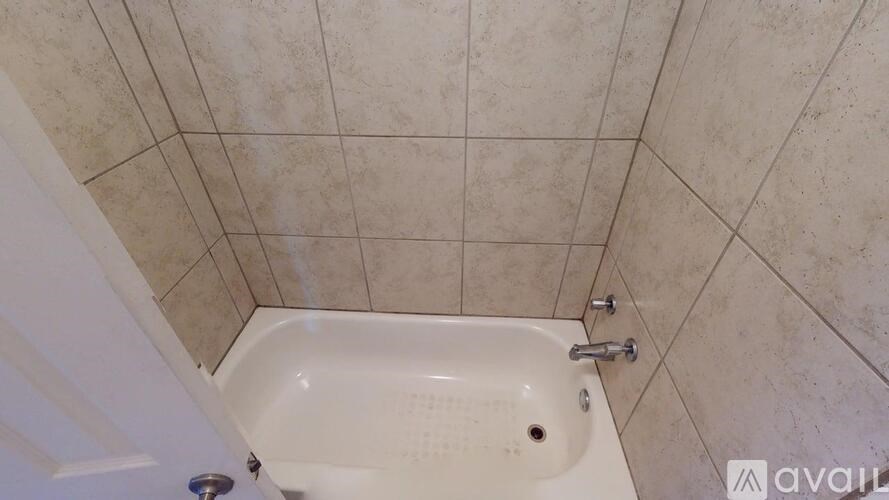 A white bathtub with a shower head and a faucet.