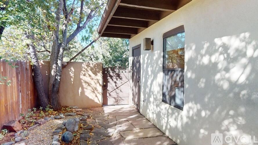 A house with a brown fence and a tree in front of it.