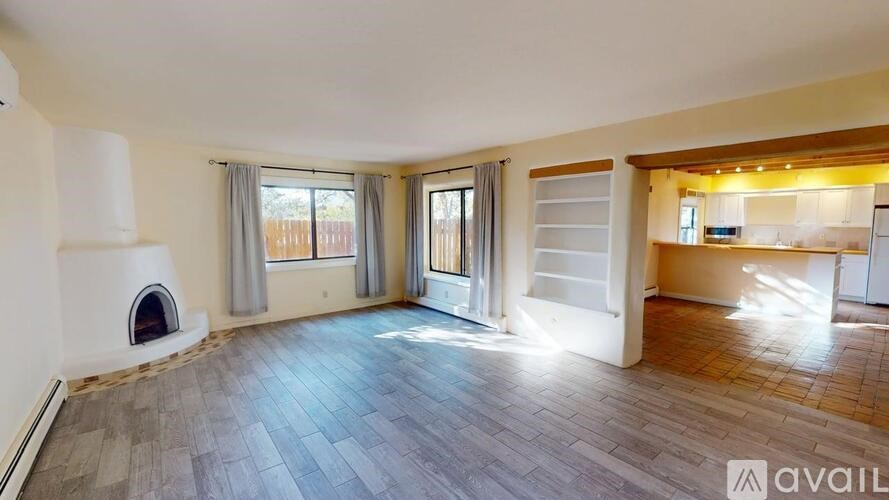 A spacious room with a fireplace and wooden flooring.