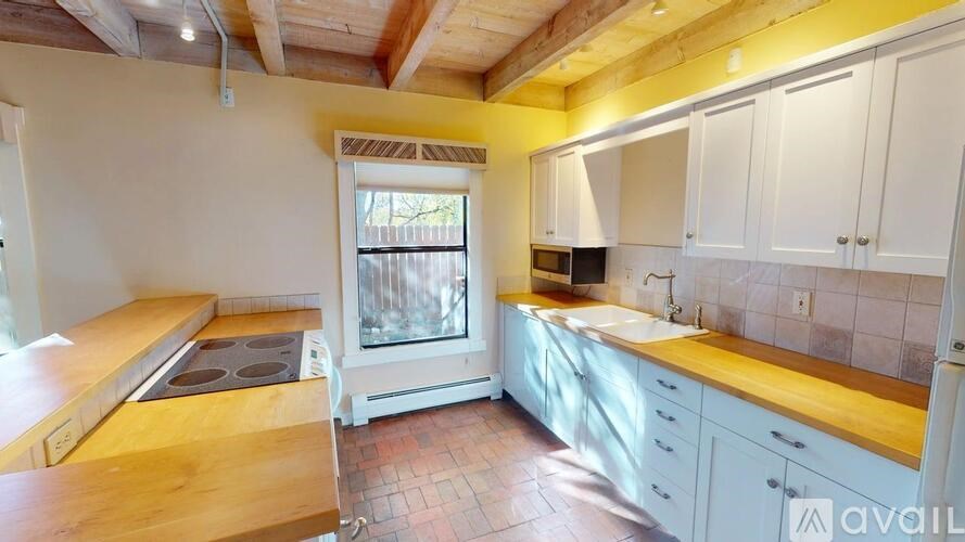 A kitchen with white cabinets and a wooden island.