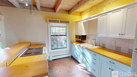 A kitchen with white cabinets and a wooden island.