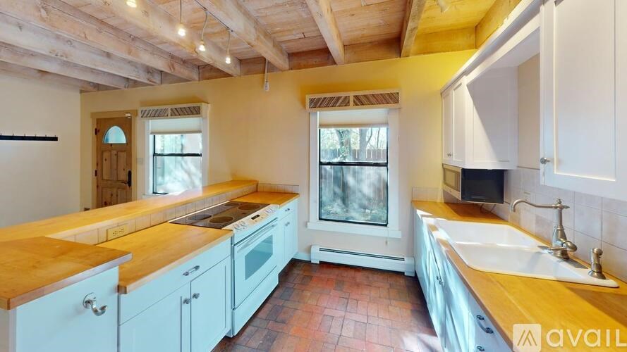 A kitchen with wooden countertops and white cabinets.