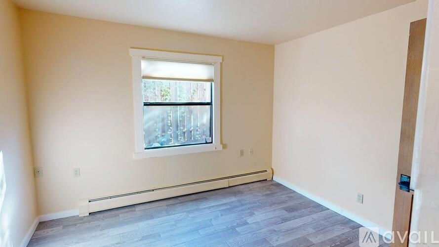 A room with a window and a wooden floor.