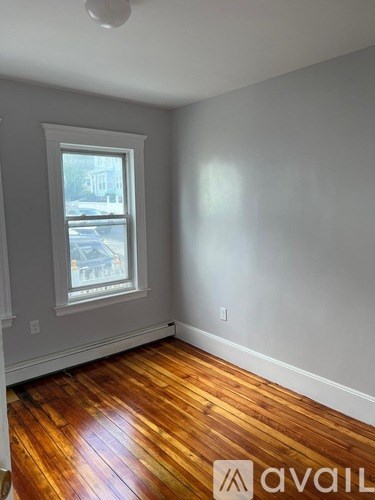 A room with wooden floors and a window showing a street view.