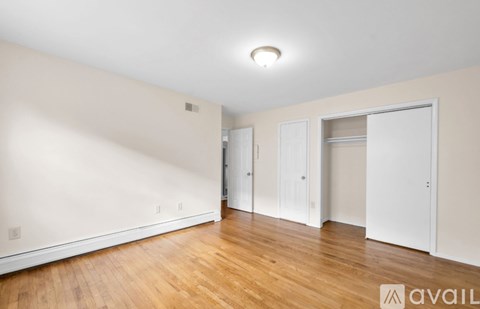 A spacious room with wooden floors and white walls.