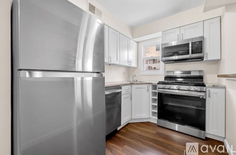 A kitchen with a stainless steel refrigerator and white cabinets.