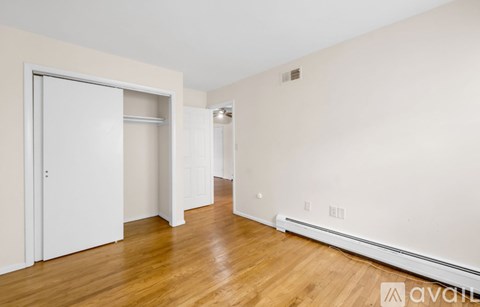A room with a white door and wooden flooring.