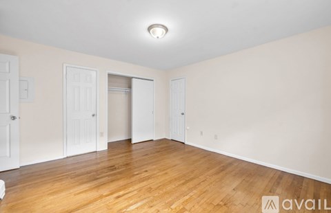 A room with wooden floors and white walls with three doors.