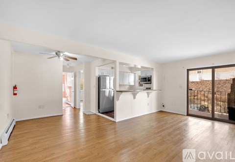 A spacious living room with wooden floors and a ceiling fan.