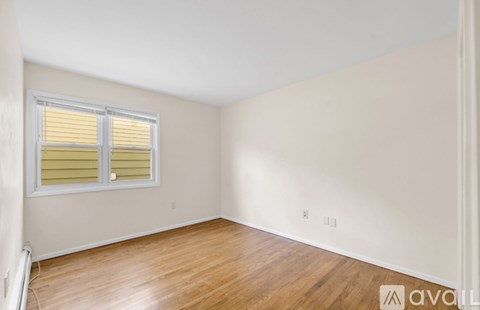 A room with wooden flooring and a window with yellow blinds.