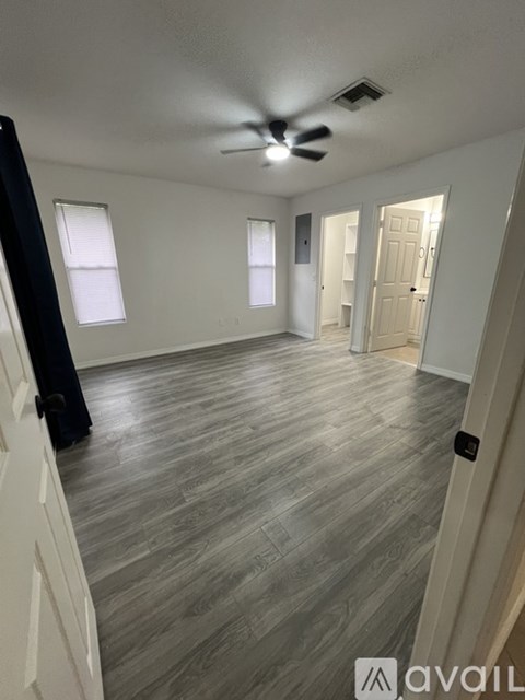 A room with a ceiling fan and wooden flooring.