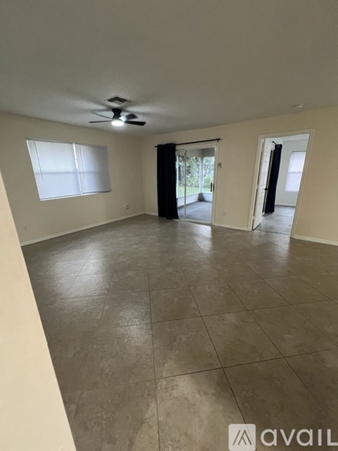A spacious room with tile flooring and a ceiling fan.
