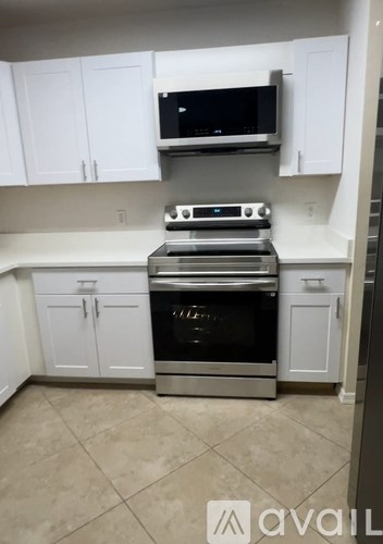 A kitchen with white cabinets and a black microwave above the stove.