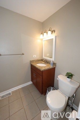 A bathroom with a toilet, sink, and mirror.