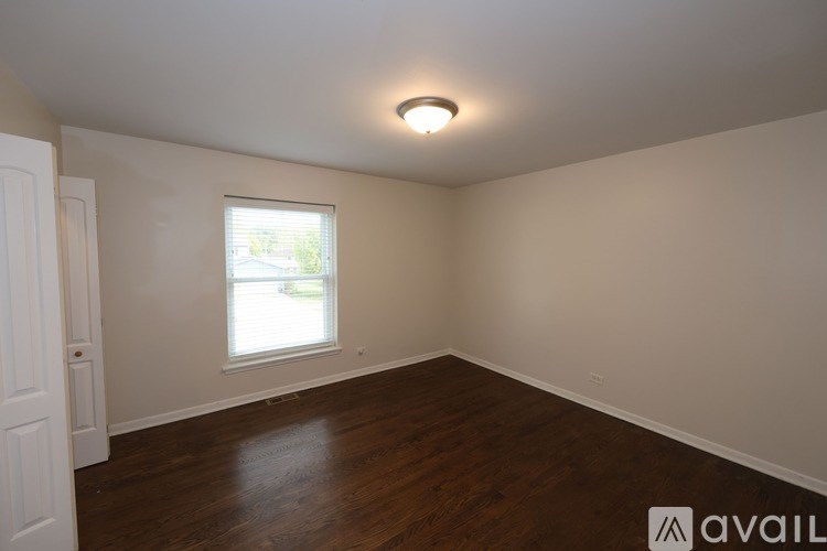 A room with wooden floors and a window letting in natural light.