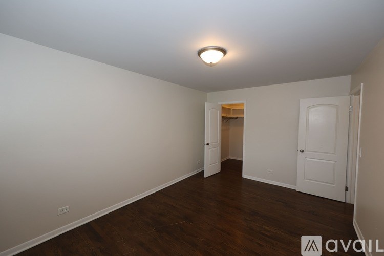 A room with a white ceiling and wooden floors, with a door on the right and another door in the distance.