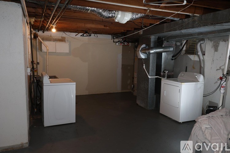 A room with a white washing machine and dryer in a basement.
