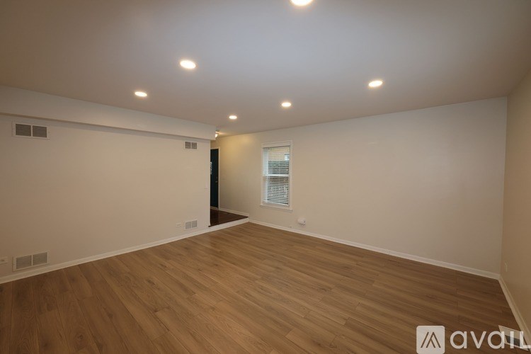 A spacious room with wooden flooring and recessed lighting.