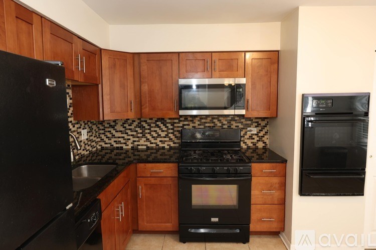 A kitchen with black appliances and wooden cabinets.