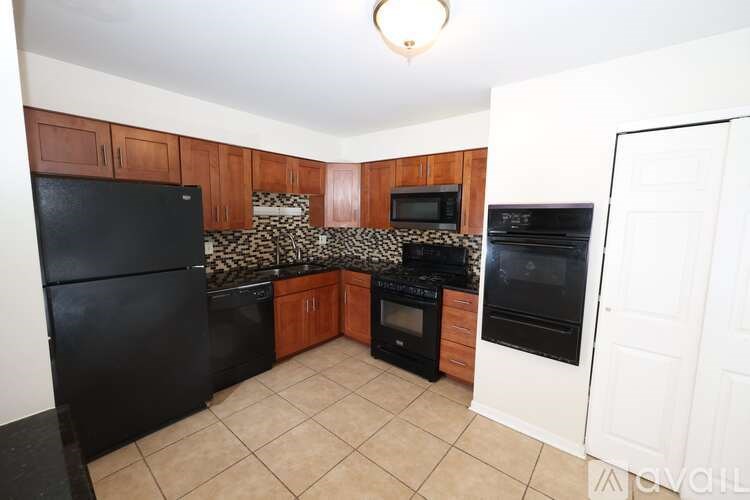 A kitchen with black appliances and wooden cabinets.