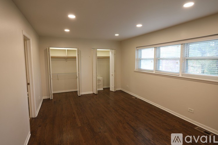 A room with wooden floors and a window with blinds.