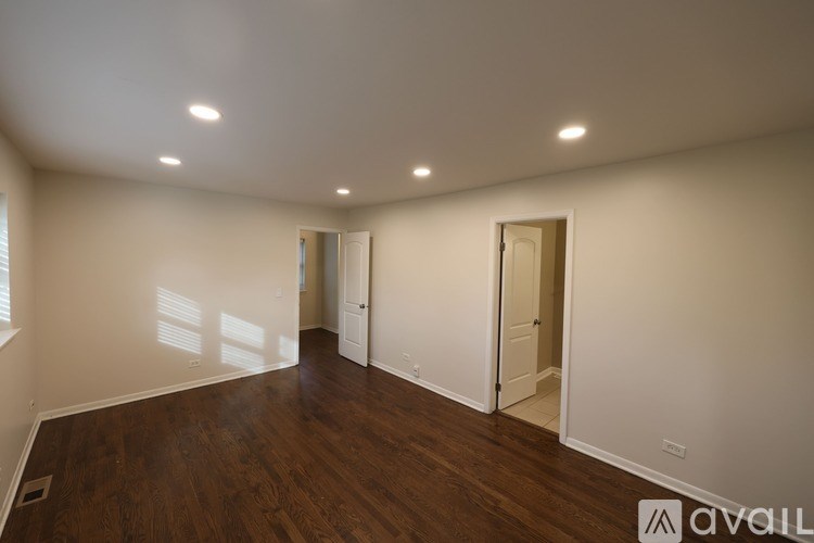 A spacious room with wooden floors and white walls.