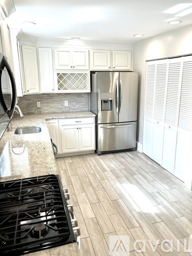 A kitchen with a stove, sink, and refrigerator.
