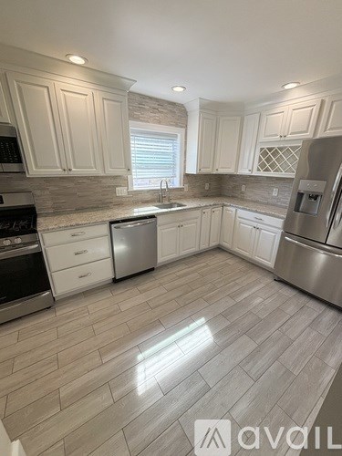 A kitchen with white cabinets and a tile floor.