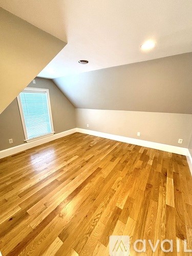 A room with wooden flooring and a window with blinds.