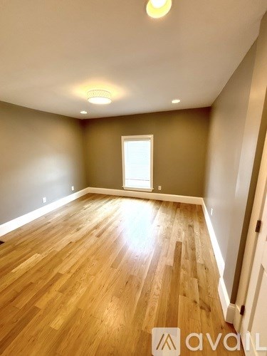 A room with wooden floors and a window letting in sunlight.