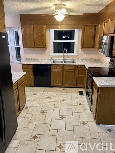 A kitchen with wooden cabinets and a black refrigerator.