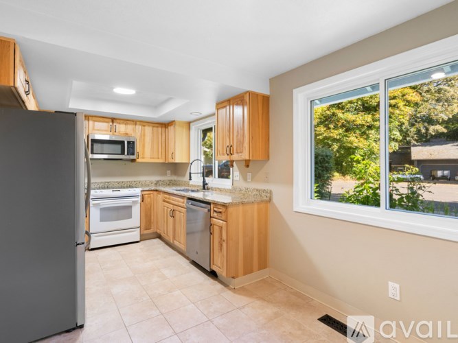 A kitchen with wooden cabinets and a large window.