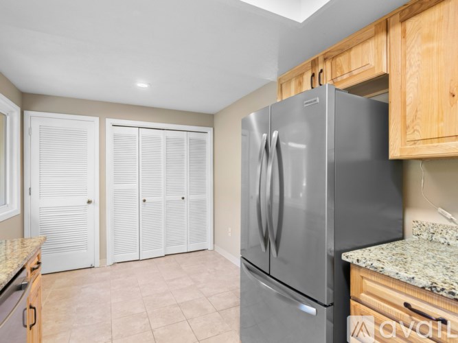 A kitchen with a stainless steel refrigerator and wooden cabinets.