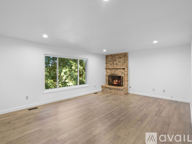 A spacious room with a fireplace and a large window.