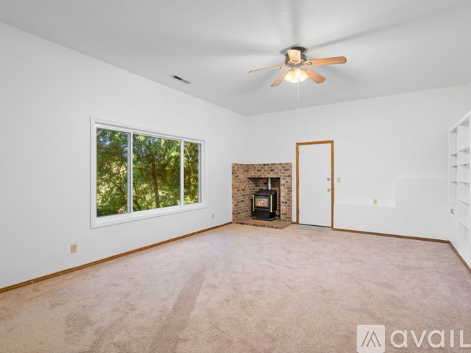 A spacious room with a fireplace and a ceiling fan.