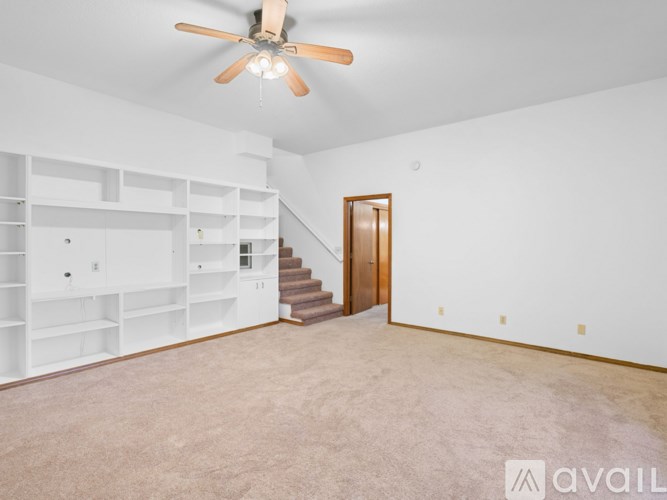 A spacious room with a staircase and a ceiling fan.