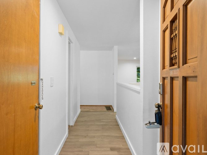 A hallway with wooden doors and a white wall.