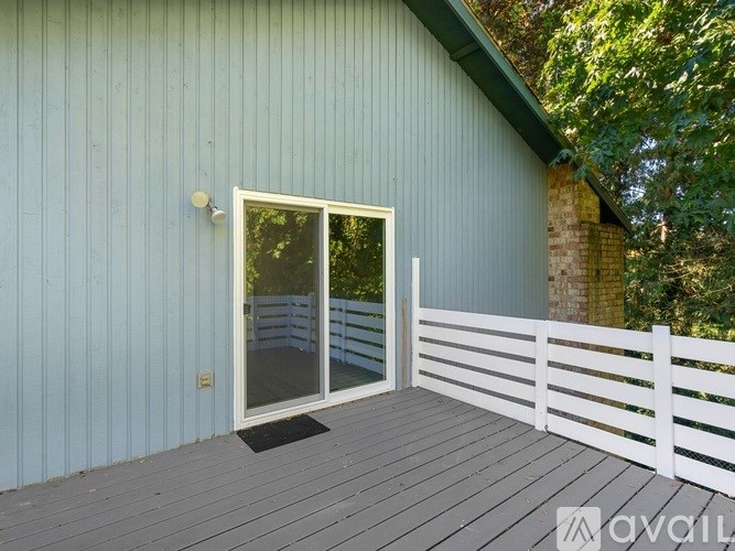 A deck with a white railing and a glass door leading to a balcony.