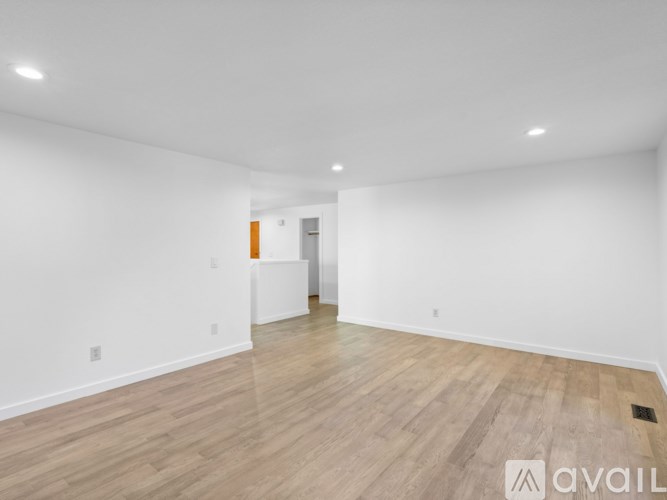 A spacious room with wooden flooring and white walls.