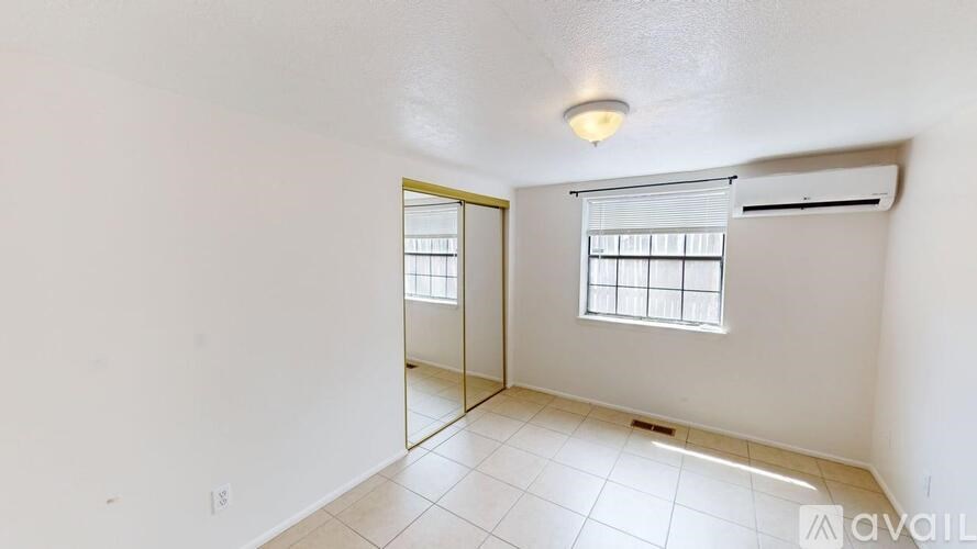 A room with a window and a mirror on the wall.