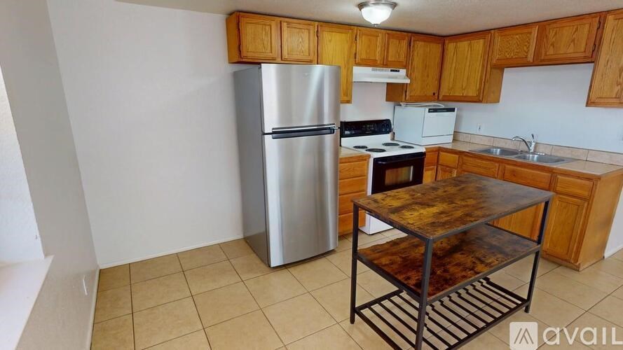 A kitchen with wooden cabinets and a stainless steel refrigerator.