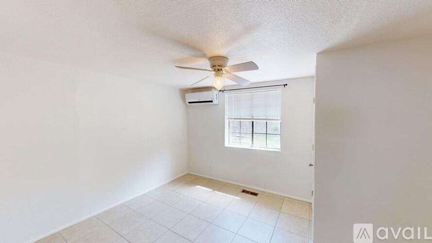 A room with a ceiling fan and a window with blinds.