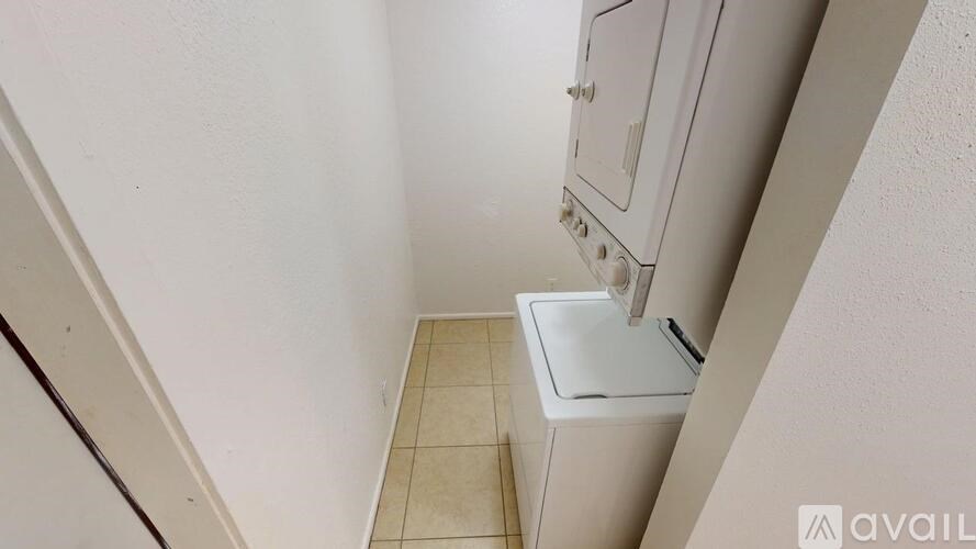 A white washing machine is in a small, tiled laundry room.