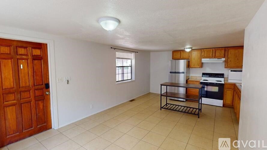 A kitchen area with a wooden door, a window, a sink, and a stove.