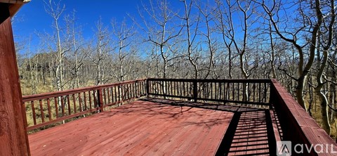 A wooden deck with a railing overlooking a forest.