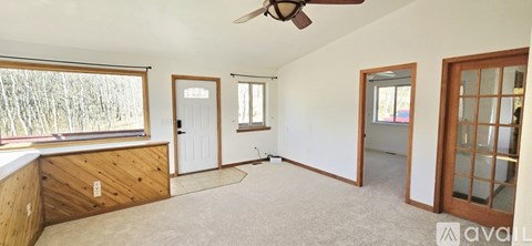 A room with a ceiling fan and a window with a view of trees.
