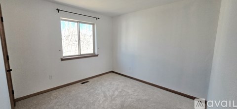A room with a window and a carpeted floor.