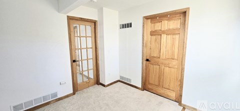A room with two doors, one with a glass panel and the other with a wooden panel.