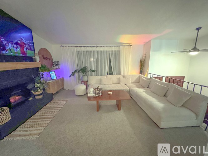 A living room with a white couch and a television on the wall.