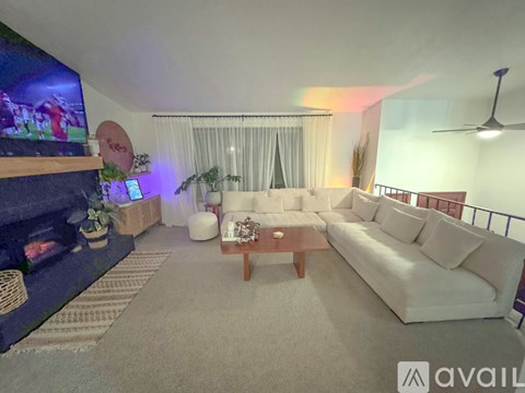 A living room with a white couch and a television on the wall.